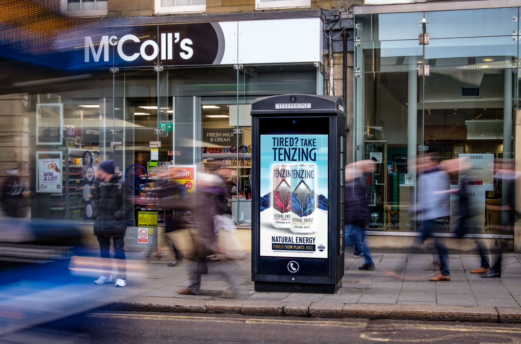 Phone box digital screen outside McColl's showing ad for Tenzing