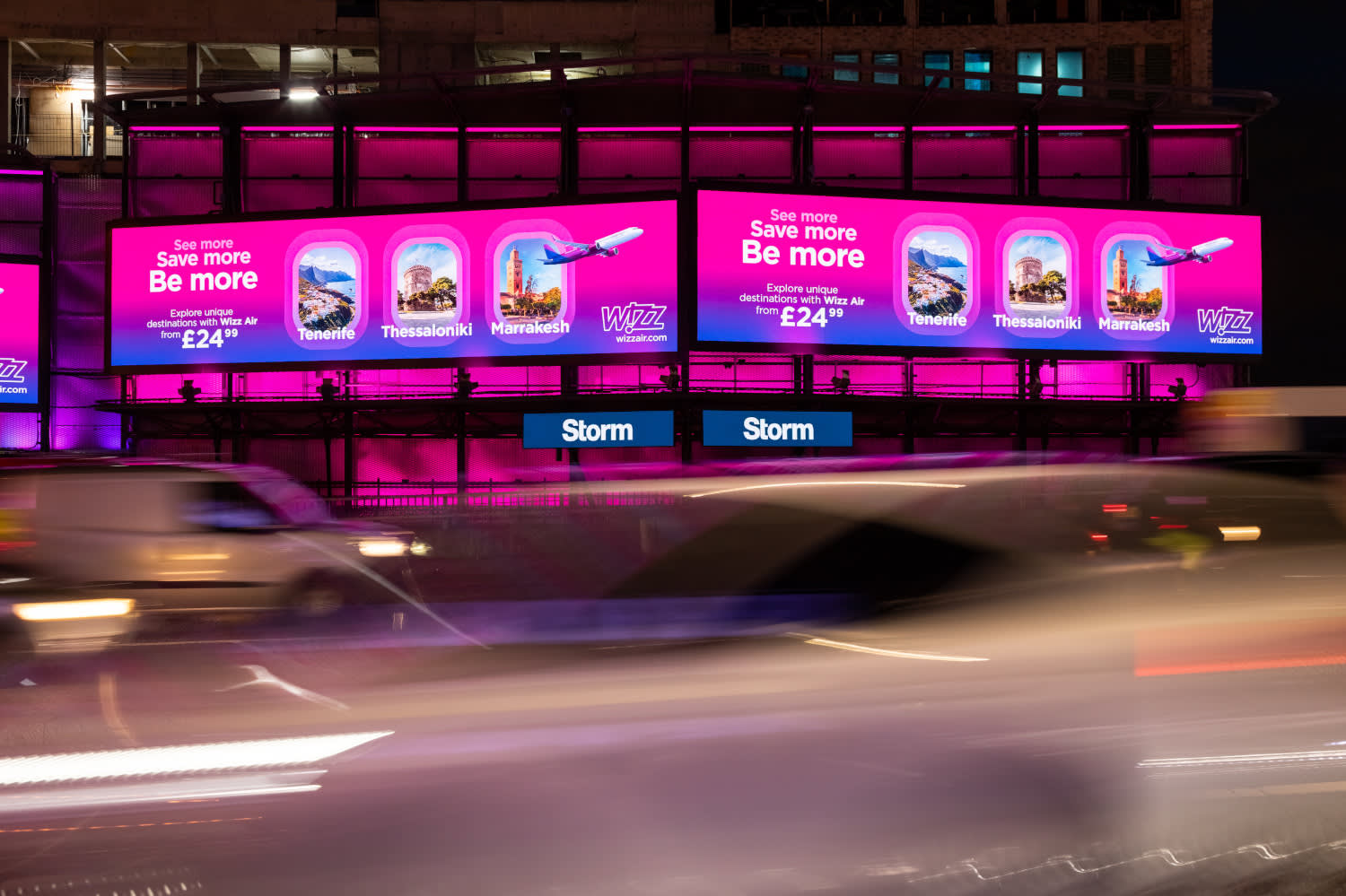 Storm Cromination in London displaying a bright pink and purple Wizz Air campaign at night