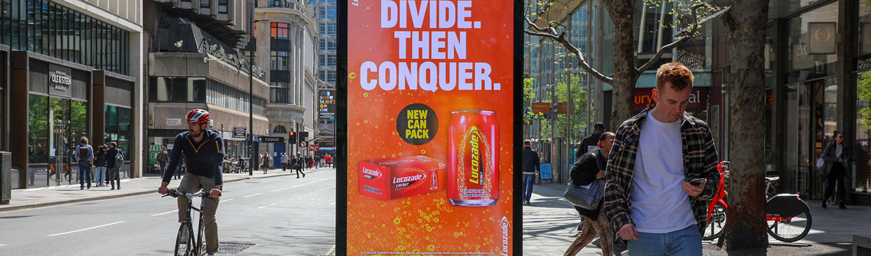 Person using mobile, walking past digital advertising