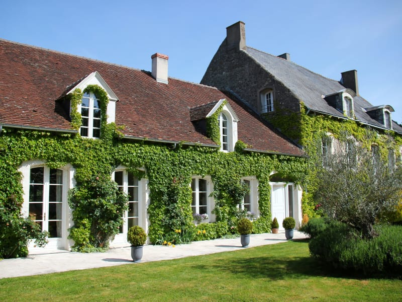 Ivy-covered French country house with dormer windows and manicured gardens.
