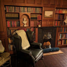 Old-fashioned hotel room with 1920s vibe. Library room with leather armchair, floor to ceiling bookcases, and fireplace.