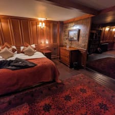 Old-fashioned hotel room with 1920s vibe. Bedroom with electric candelabra and wood panelling.