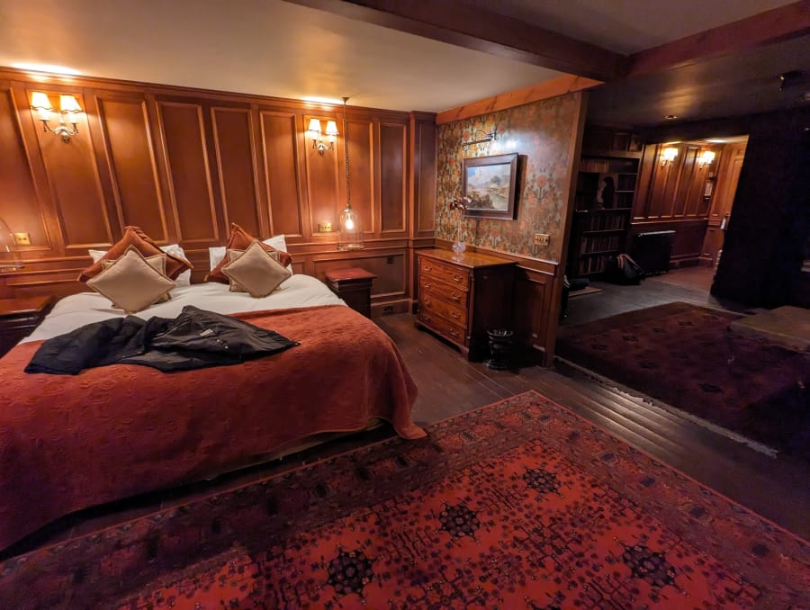 Old-fashioned hotel room with 1920s vibe. Bedroom with electric candelabra and wood panelling.