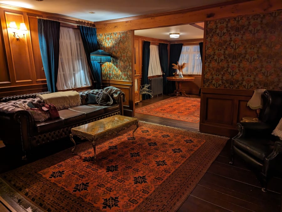 Old-fashioned hotel room with 1920s vibe. Sitting room with leather sofa and rug.