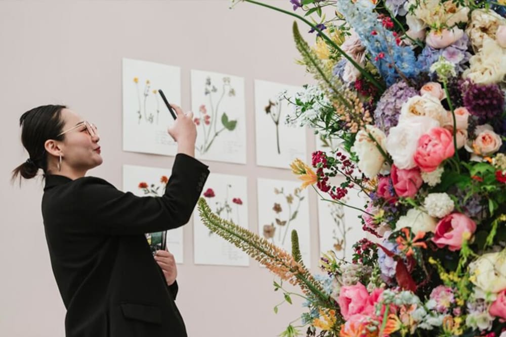 Woman taking a picture of a flower display at RHS Chelsea Flower Show