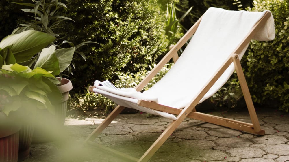 A deck chair in a patio garden surrounded by green outdoor plants