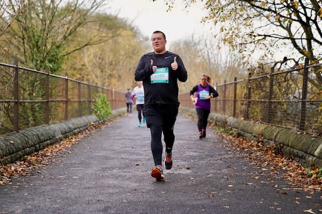 Me running towards the camera with a tired look on my face, attempting two thumbs up.