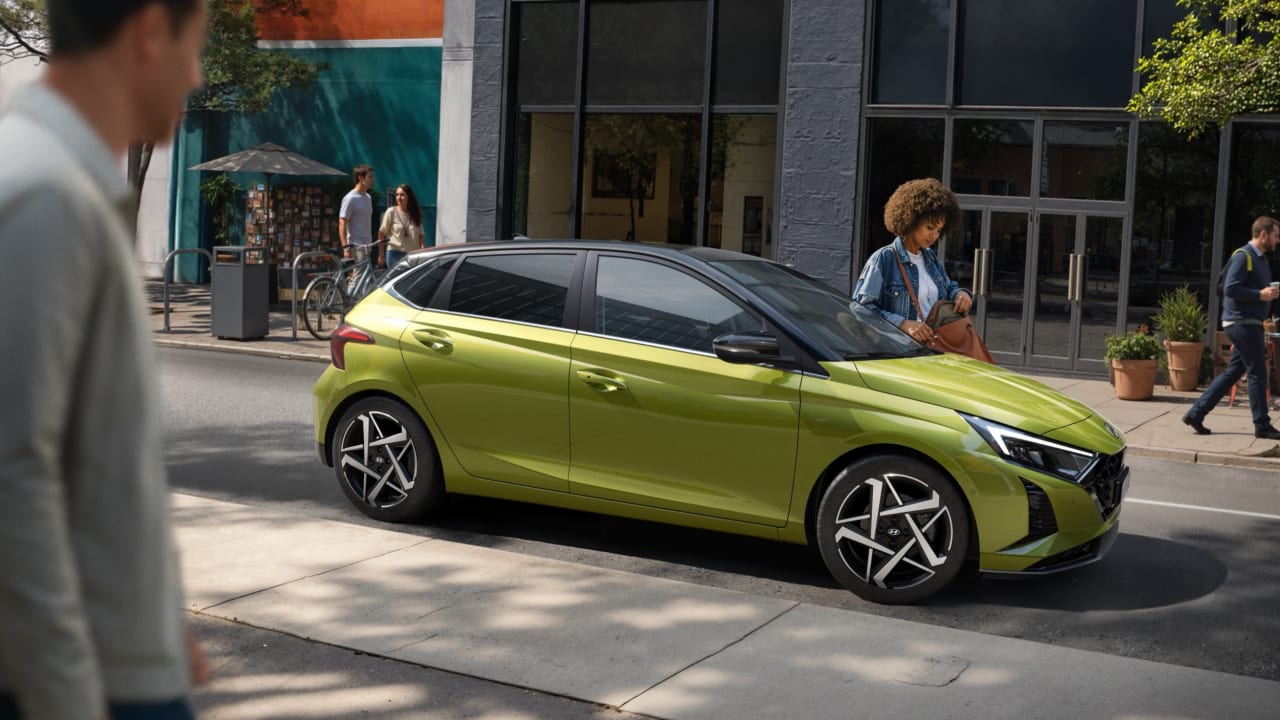 Lime green Hyundai i20 parked on a city street, side view