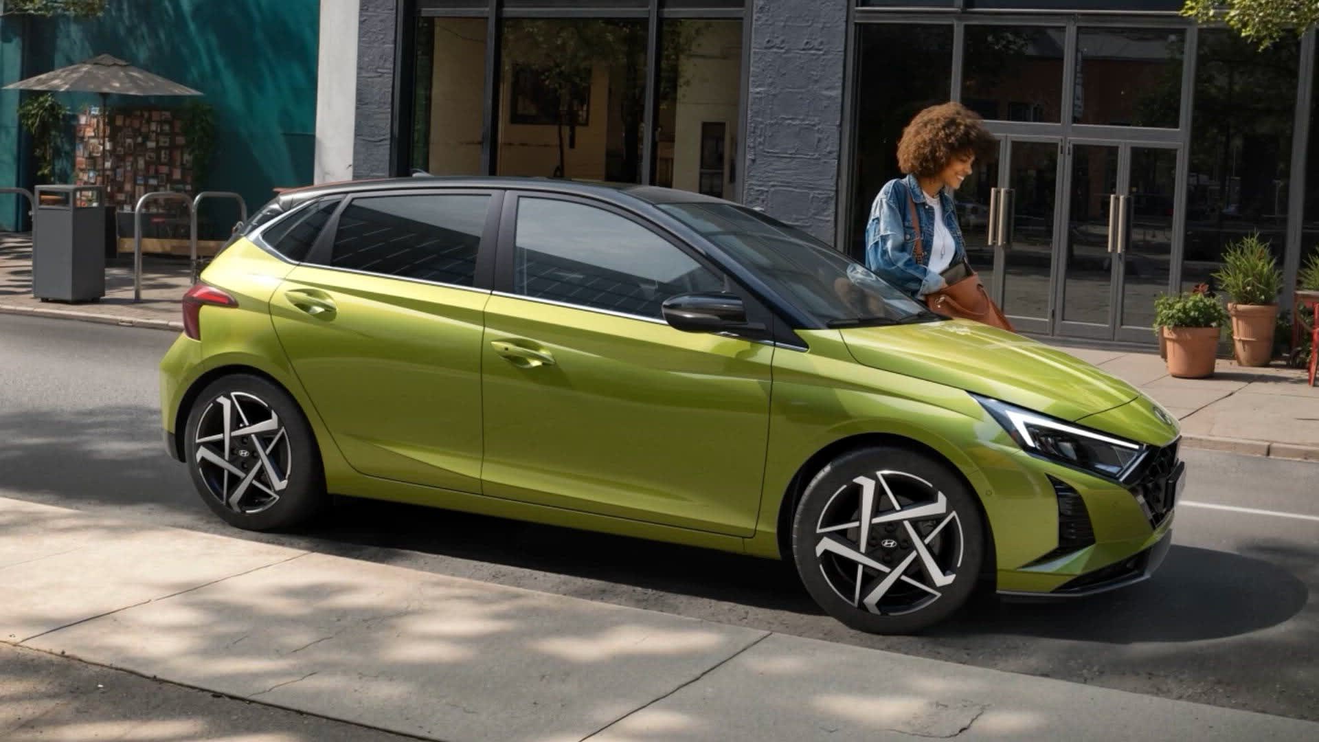 Lime green Hyundai i20 parked in the city with a woman by the door