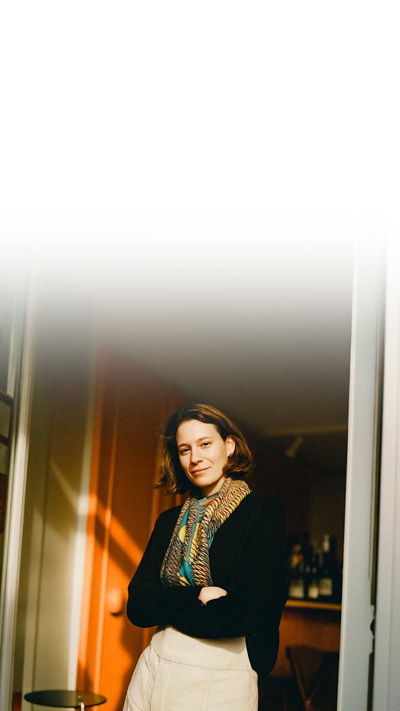 A smiling young women atanding at the door.