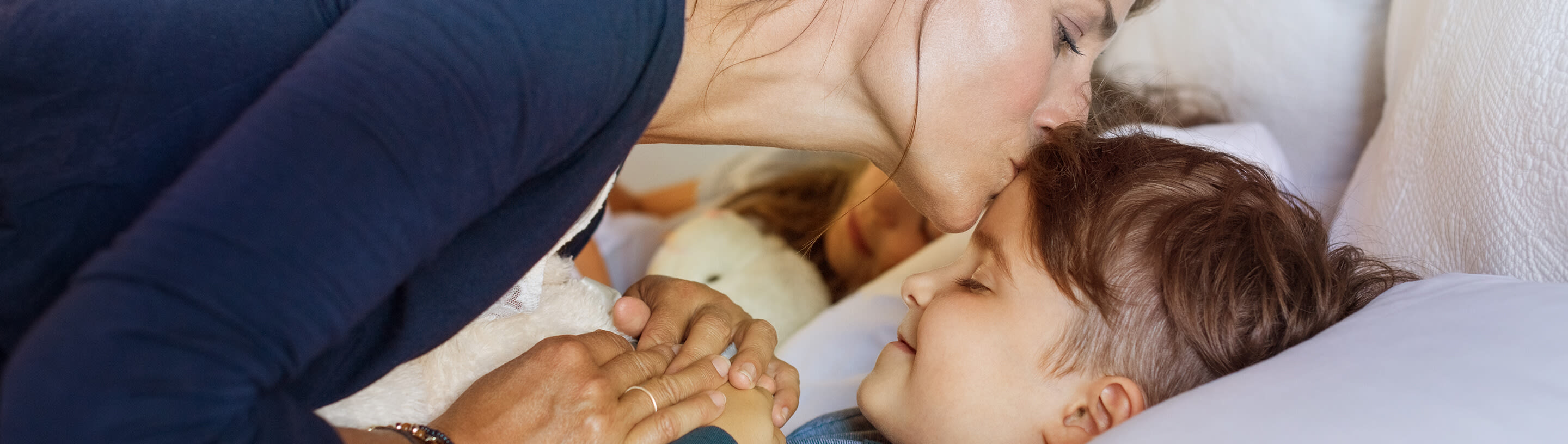 A mother gives a kiss to her child before going to bed