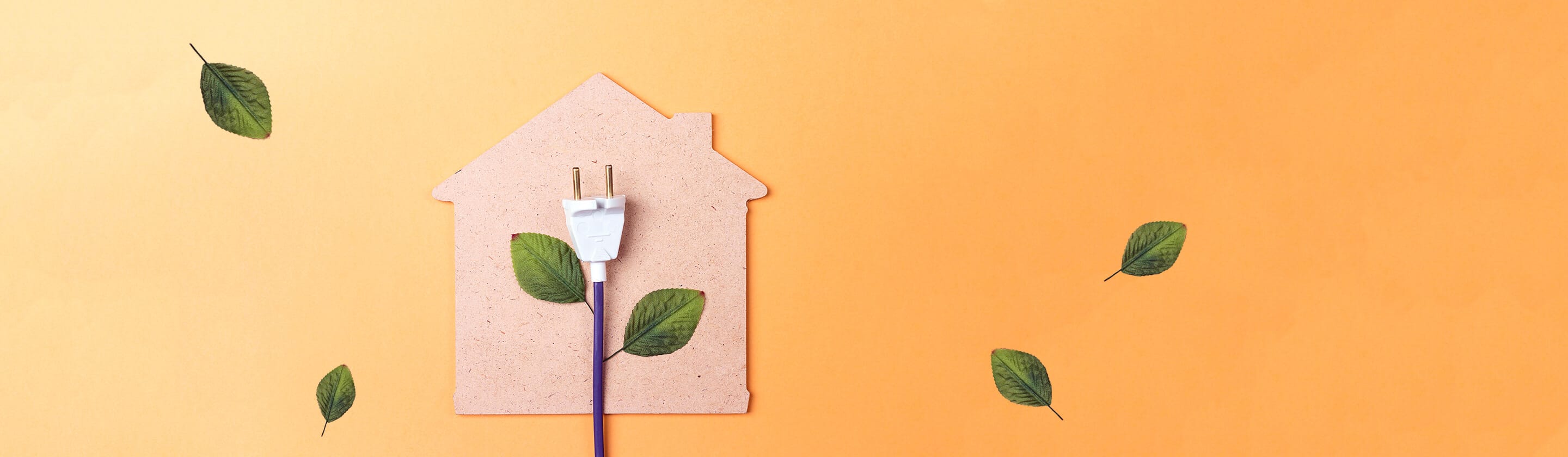 House shape cut out of cardboard on an orange background with electrical cable