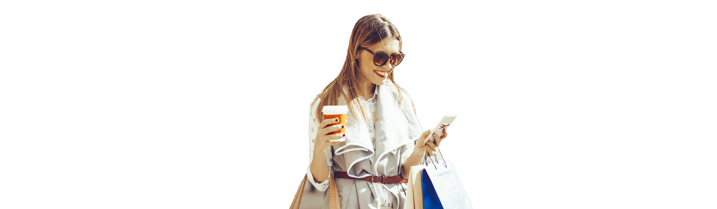 Smiling girl with glasses on the street with coffee in one hand looking at her mobile phone.