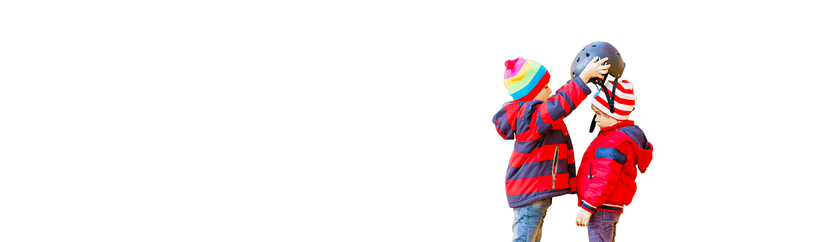 A small boy puts a protective helmet on another boy's head for cycling.