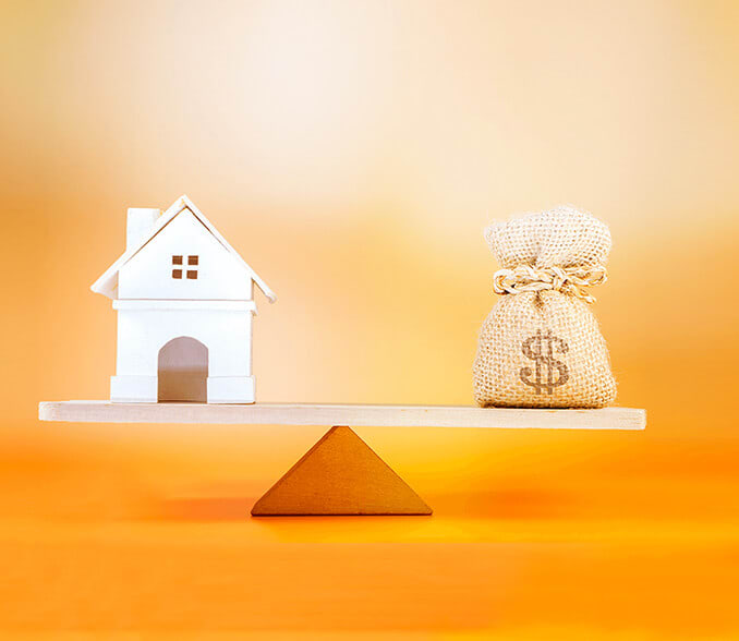 A scale in a balance. On the left scale is a house, and on the right is a bag of money.