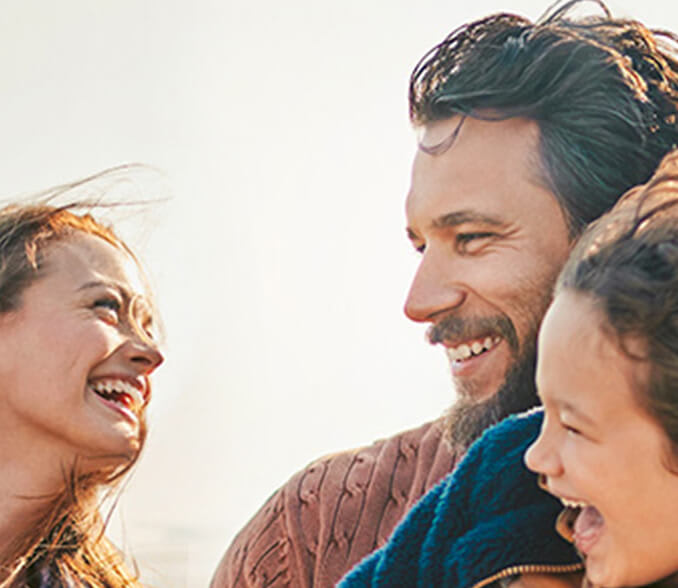 A father and mother with two children standing smiling by the beach