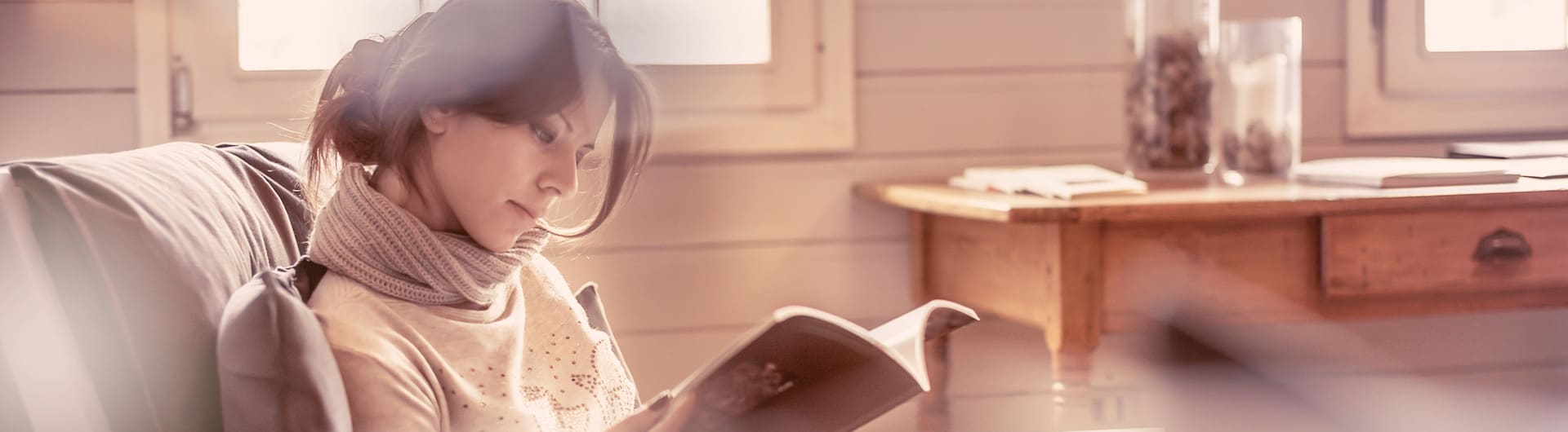 A woman in an armchair reads a book.