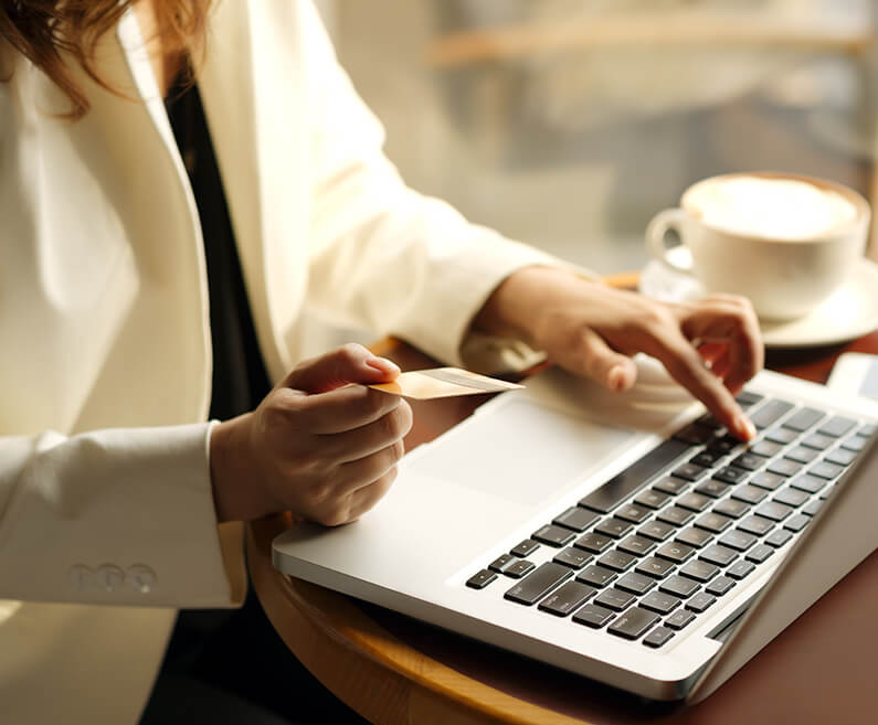 Woman with card at laptop.