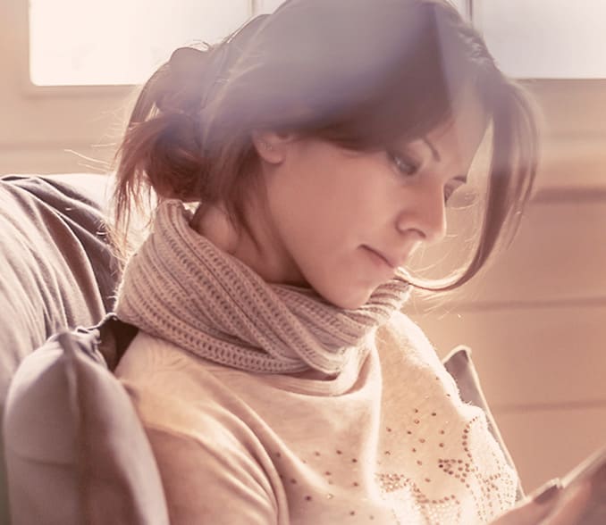 A woman in an armchair reading a book.