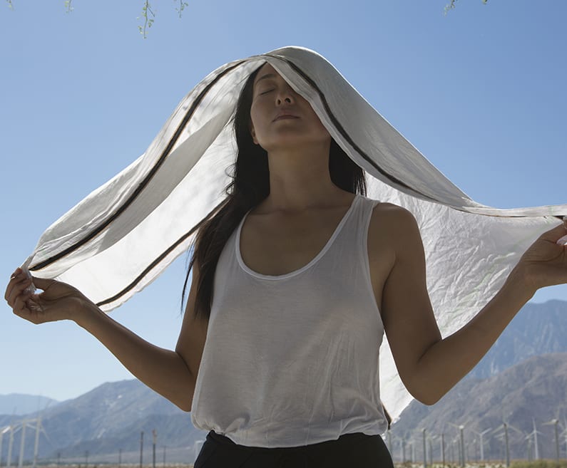 A relaxed girl with her eyes closed, covered in a white scarf.