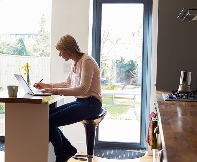 Woman in kitchen with laptop.