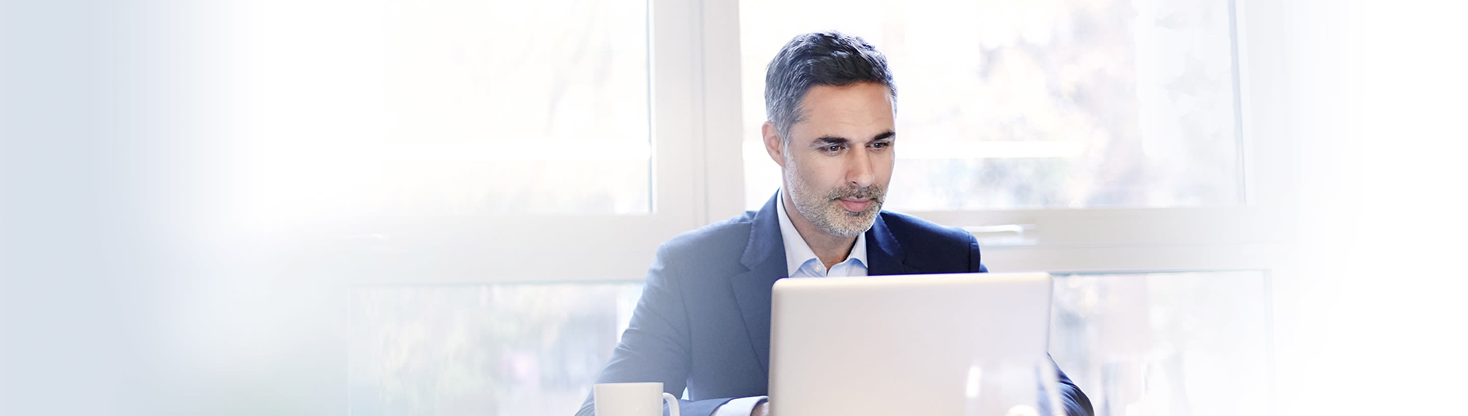A man in a suit working on a laptop.