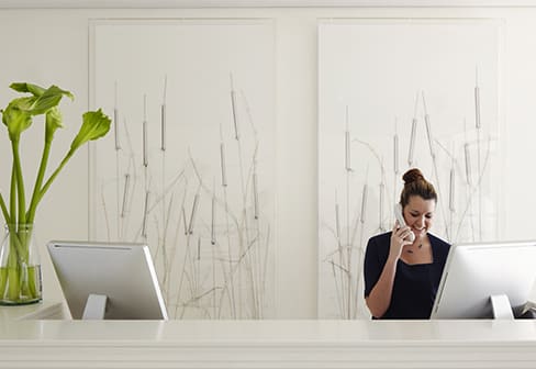 A woman at an information desk talks on the phone.