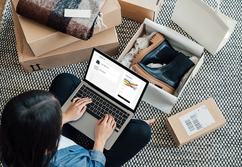 A young girl is sitting on the floor and shopping online via laptop.