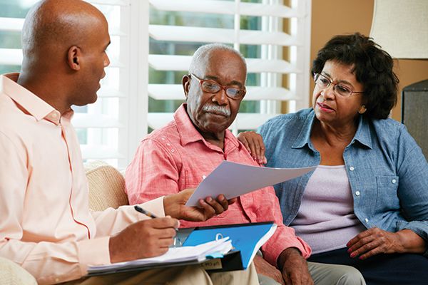 Couple talking to financial advisor holding paperwork