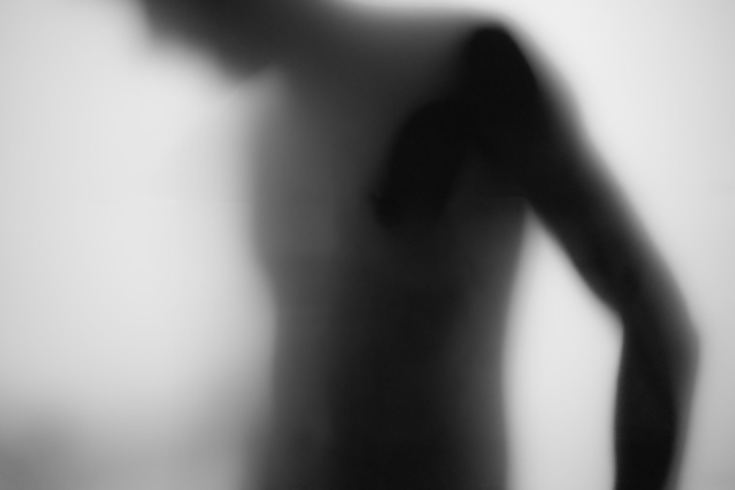 The side of a torso and arm in soft silhouette behind the glass