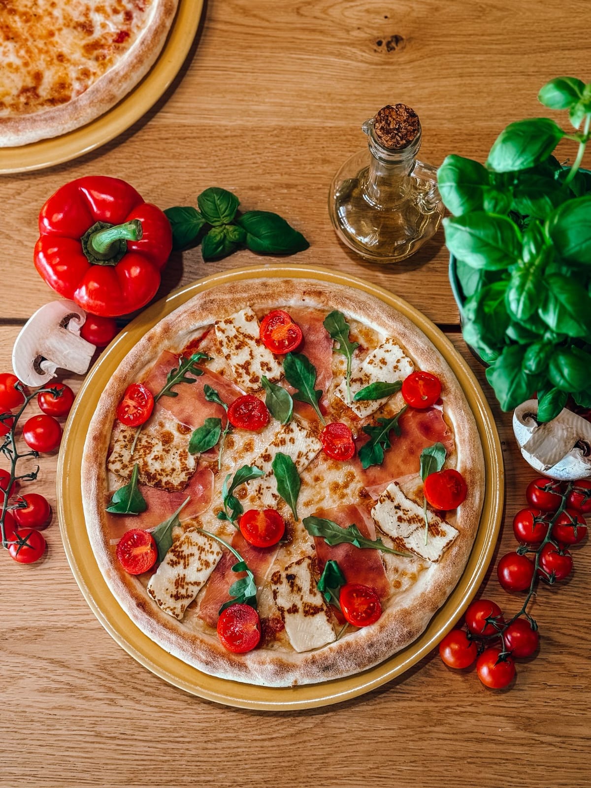 Pizza z sosem i dodatkami sfotografowana na drewnianej desce.