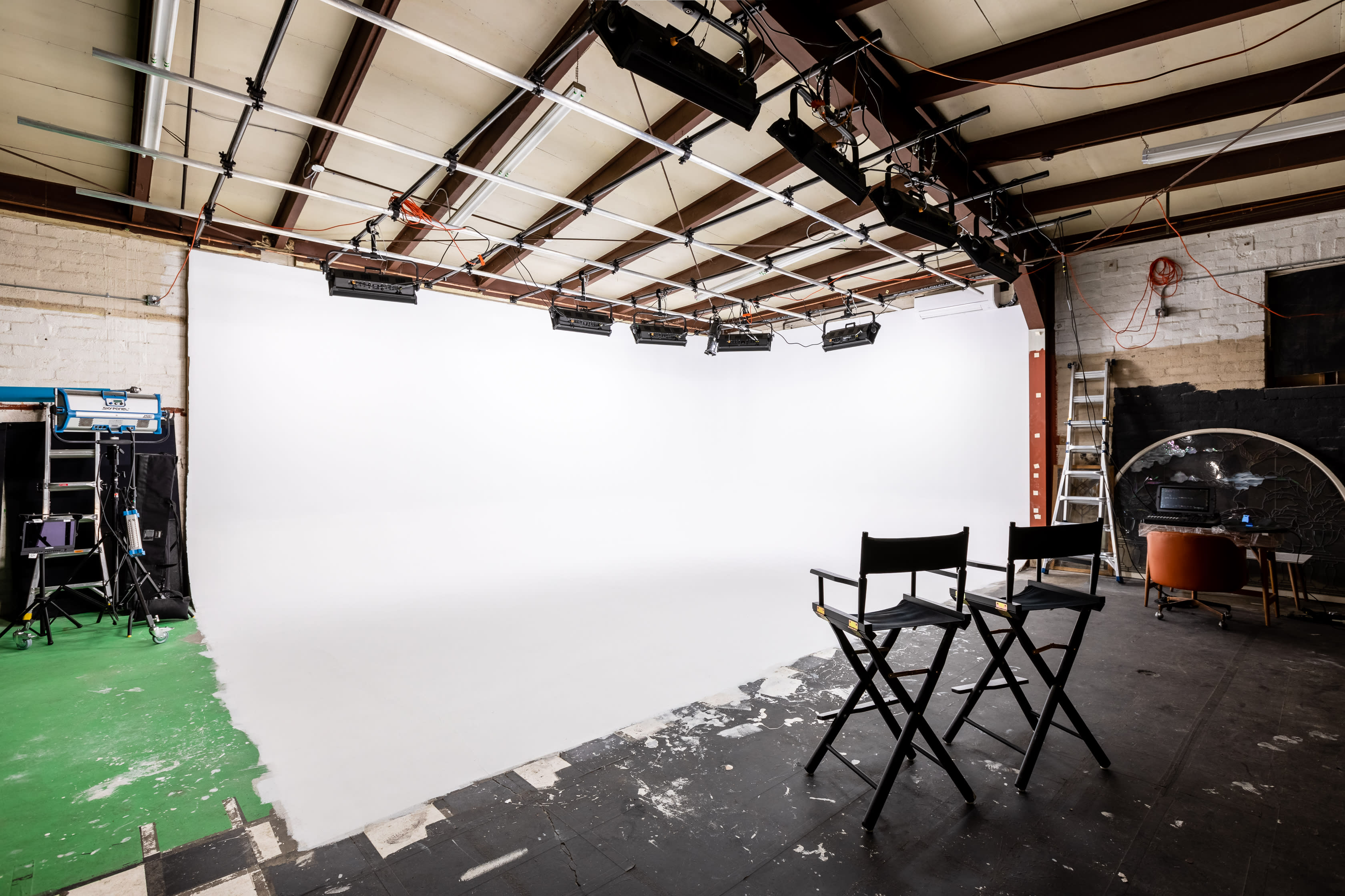 A camera crew sets up for an interview shoot, featuring a seated subject in front of a lit backdrop.