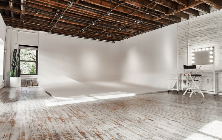 A person stands in a dimly lit room, holding a camera while capturing a scene for a music video.