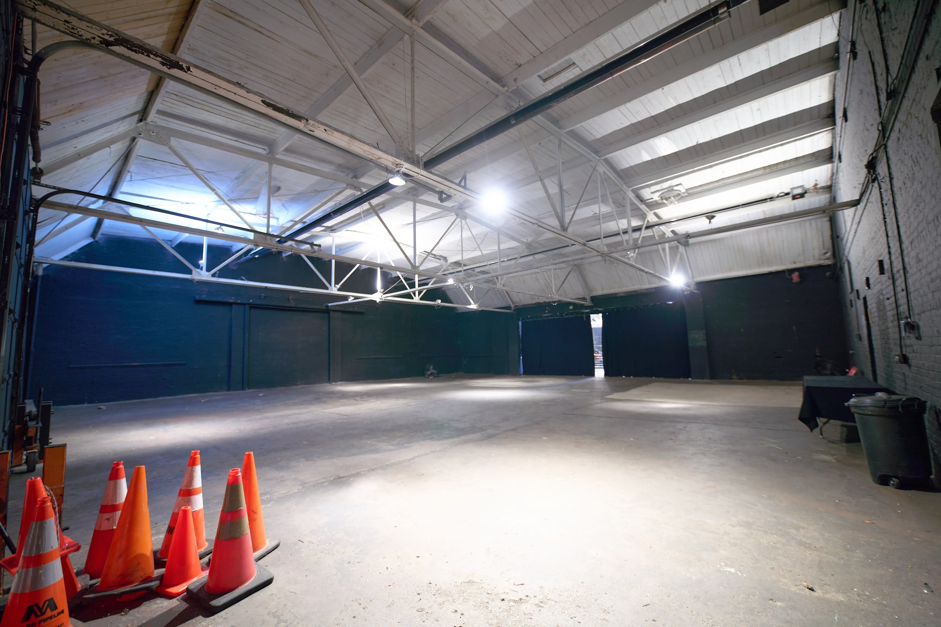 Two individuals are filming a video in a dimly lit space filled with smoke, while bright lights illuminate the background.