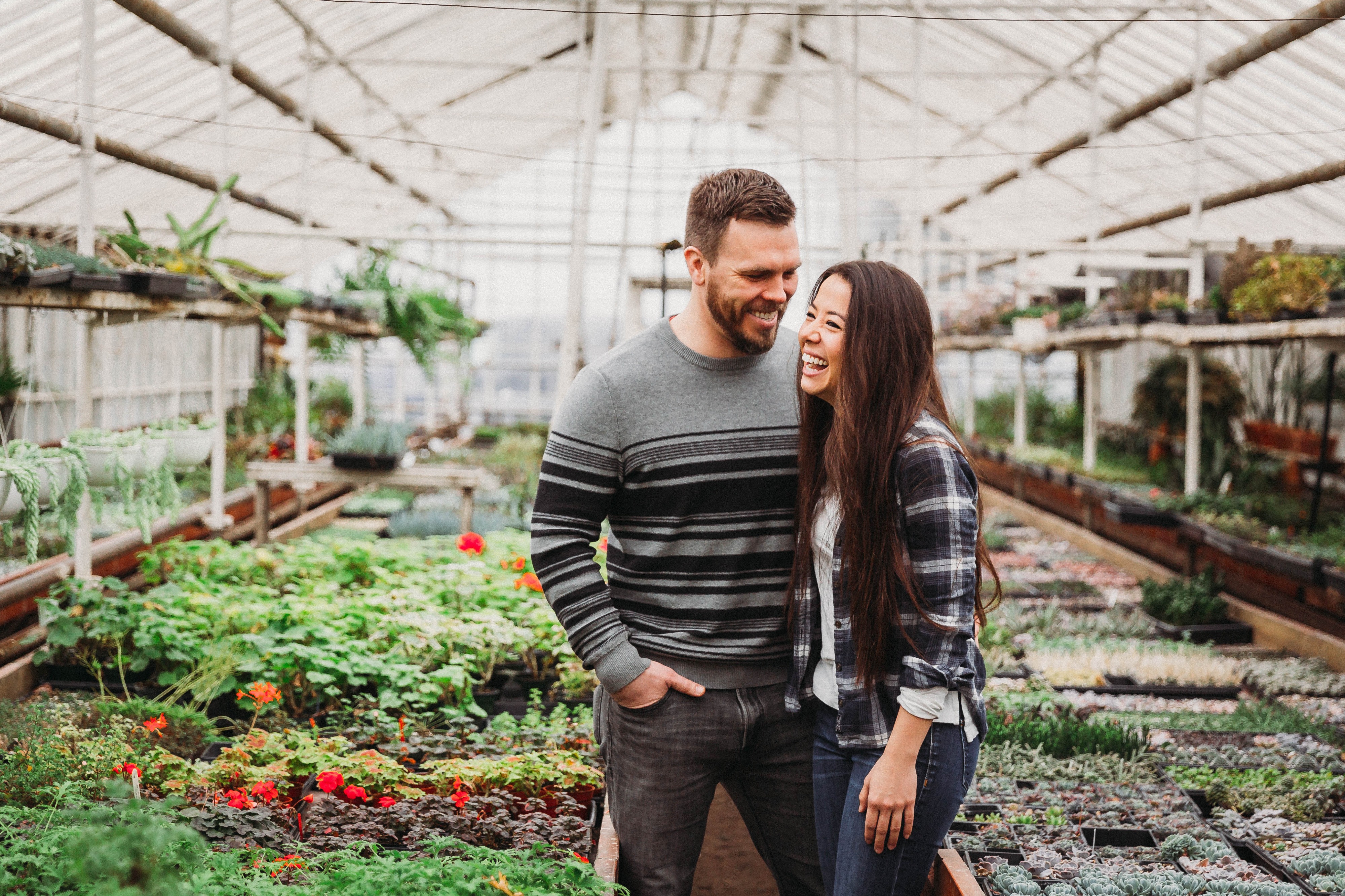 A model poses amidst lush greenery during a photo shoot in a greenhouse.