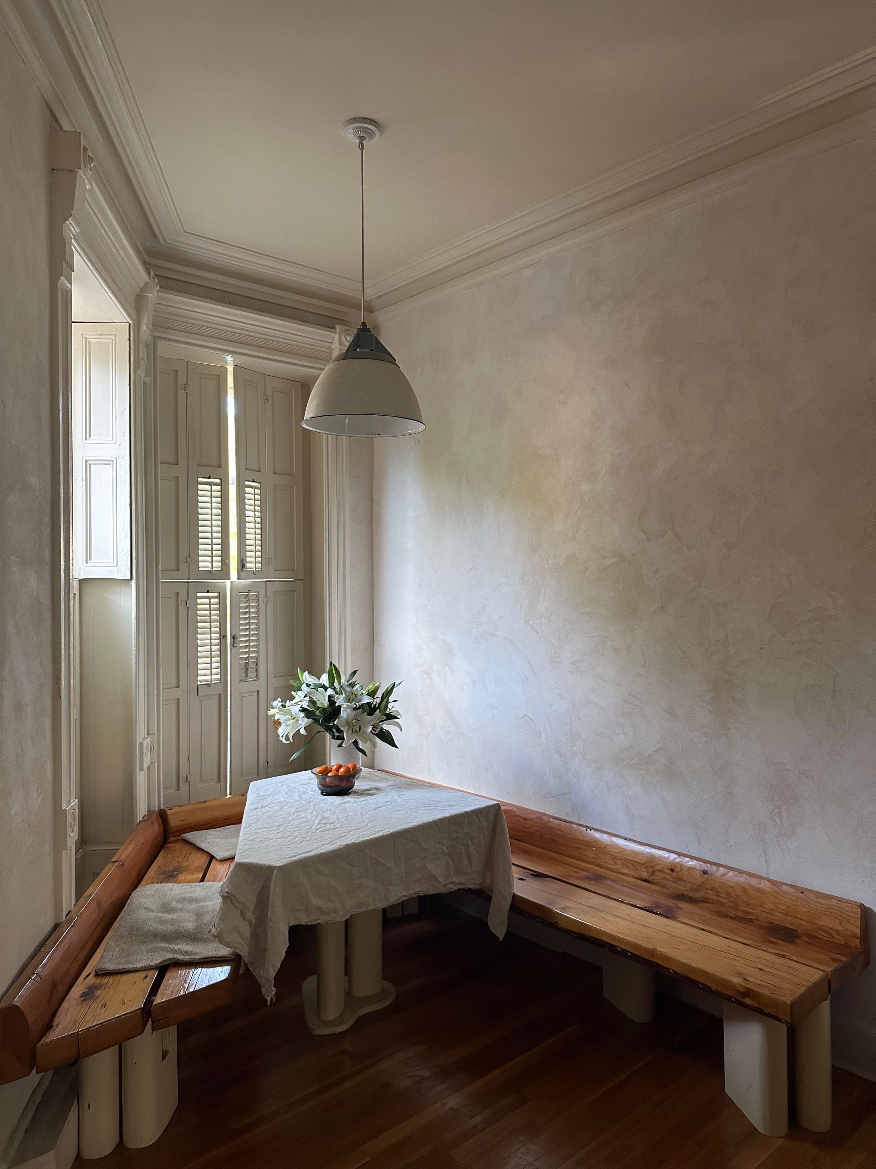 A woman in a green dress holds a bouquet of tulips while arranging a table in a well-lit room.