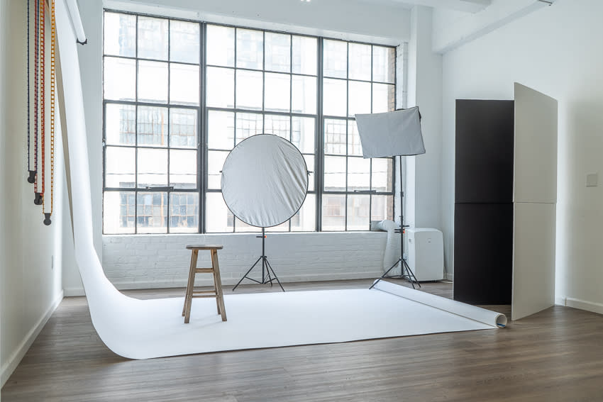 A photo shoot is taking place in a studio with large windows allowing natural light to stream in.
