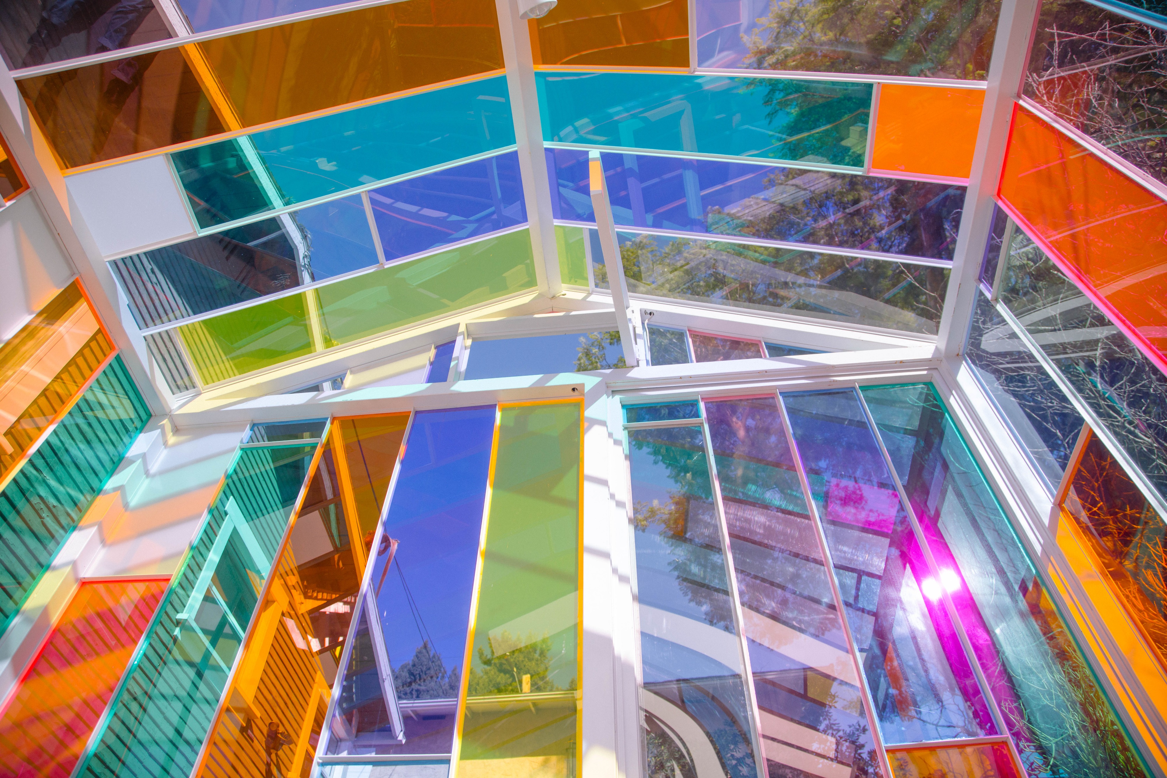 A photoshoot takes place along a colorful pathway lined with geometric glass panels reflecting vibrant light.