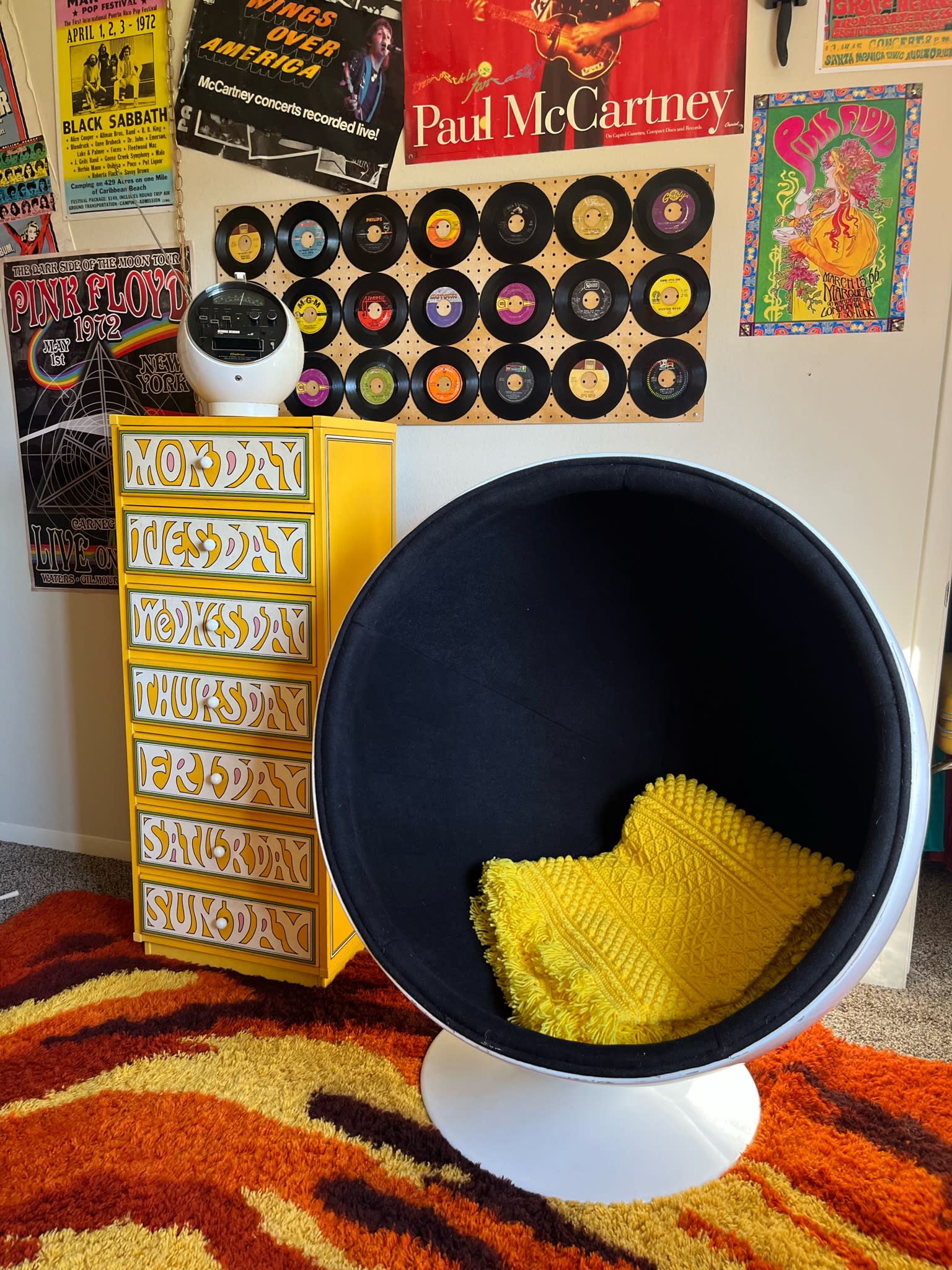 A pregnant woman in a yellow outfit opens a decorated refrigerator in a kitchen.