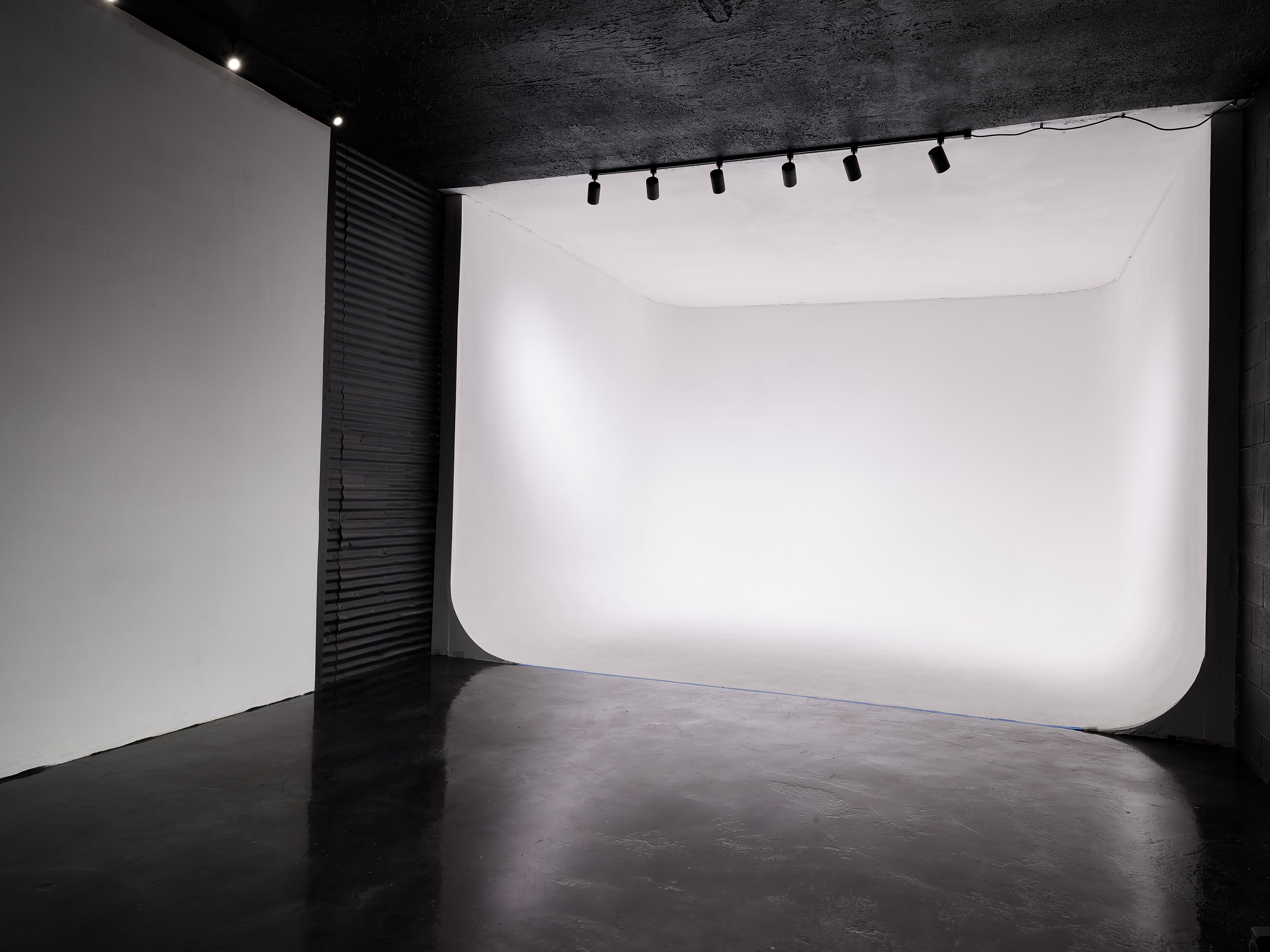 Three individuals pose playfully in a studio during a video shoot.