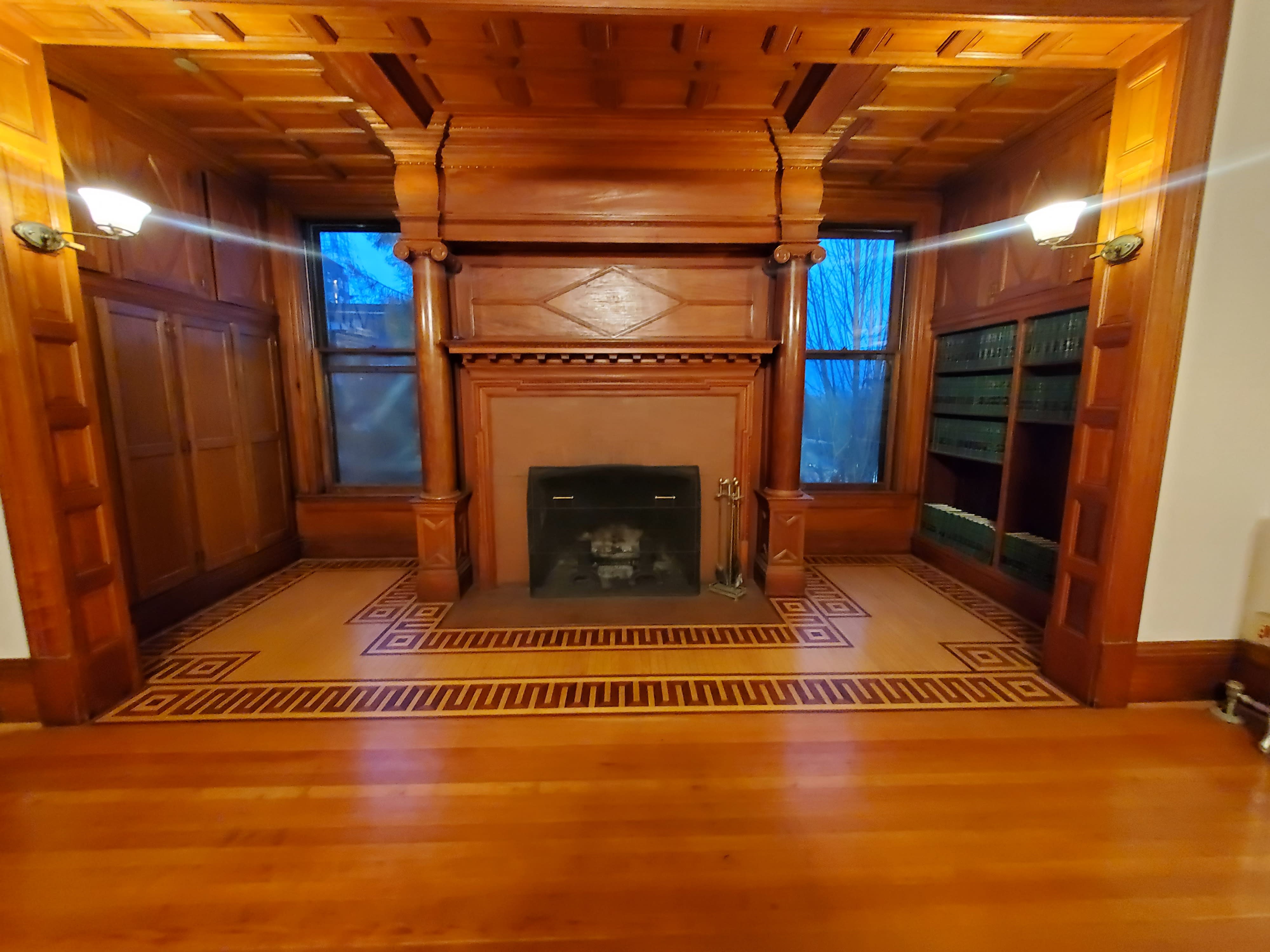 The elegantly decorated room features a fireplace adorned with greenery, a round table set for refreshments, and a chair beside a ring light for capturing memories during a wedding ceremony or event.