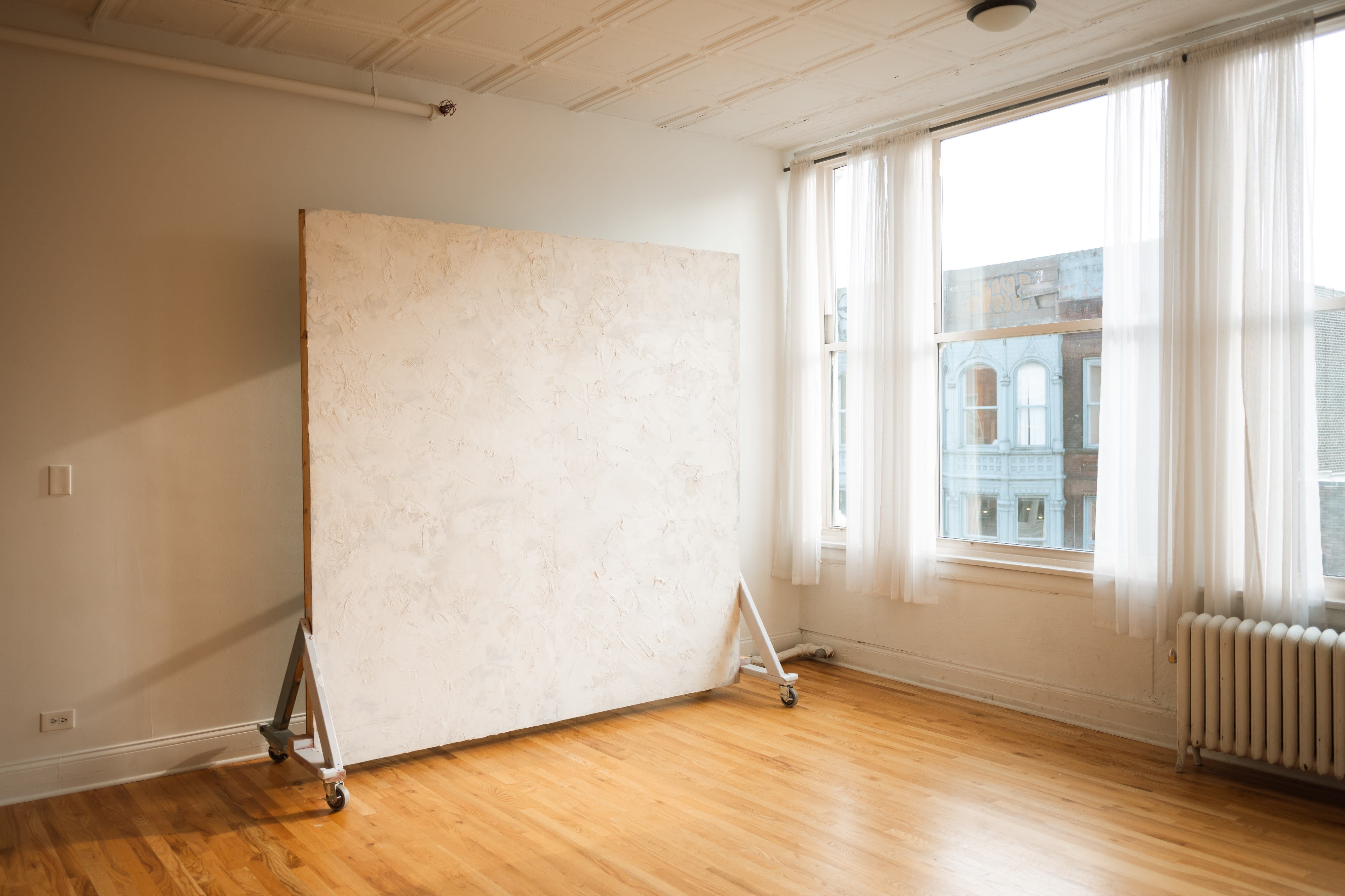 Two women examine artwork displayed on easels in a bright, airy gallery.