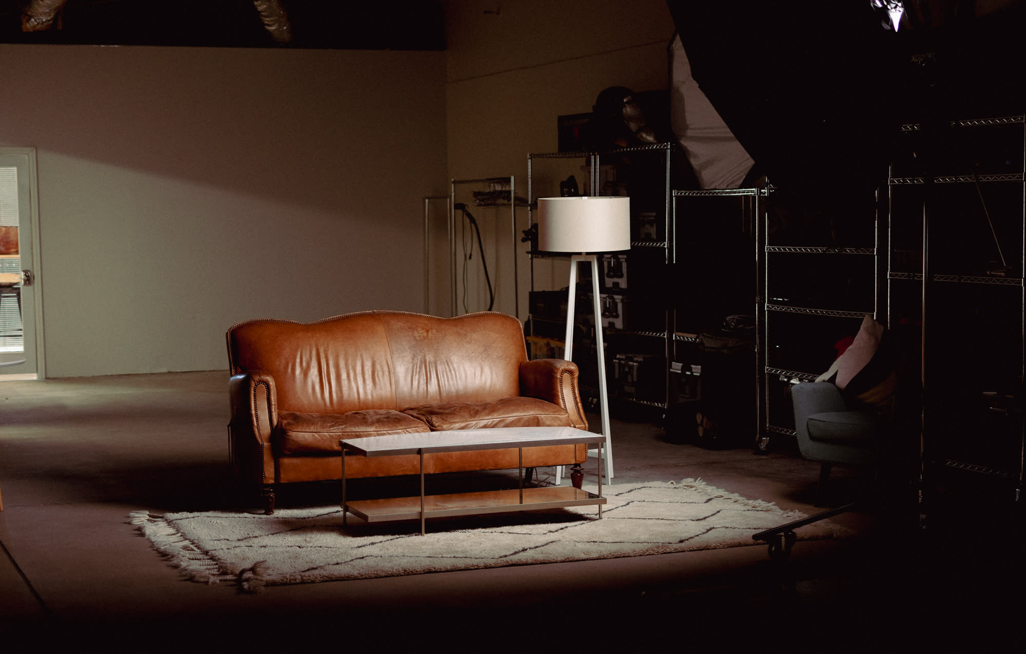 A model lies on the studio floor wearing a textured coat during a photoshoot.