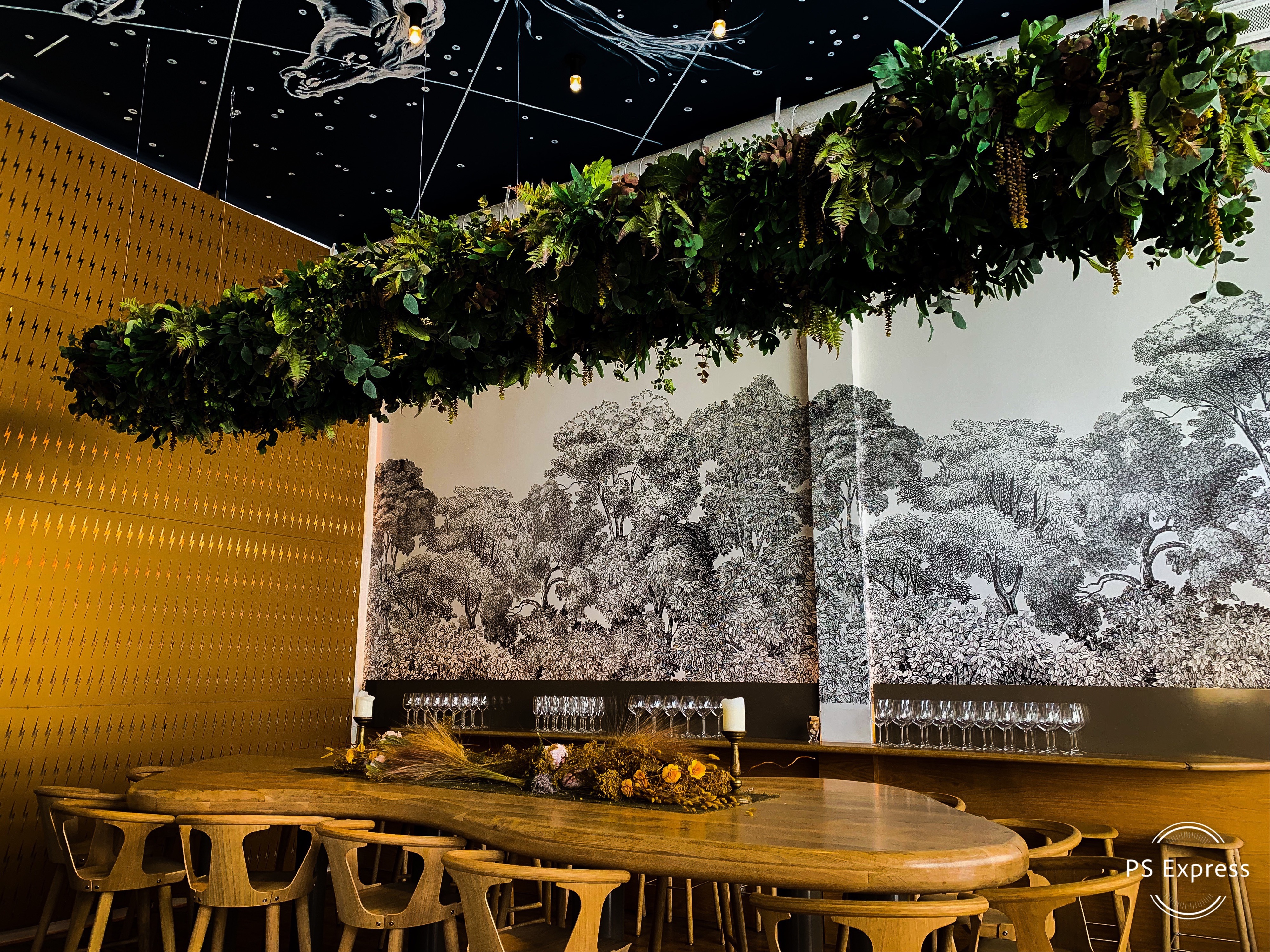Guests gather around tables decorated with food and drinks at a festive baby shower celebration.