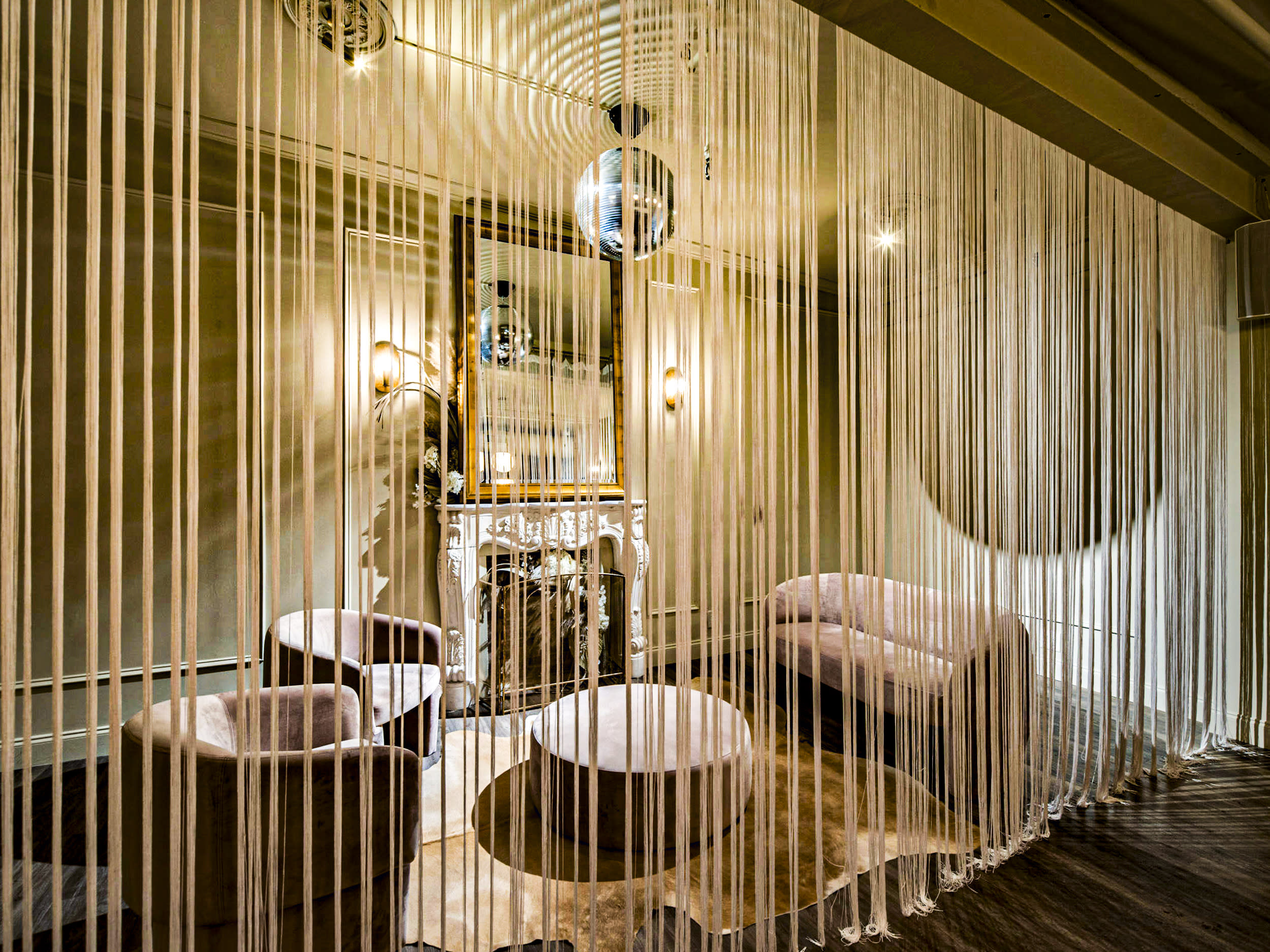 A bride and groom pose together, showcasing the bride's ring, in a decorated reception area with soft lighting and elegant furnishings.