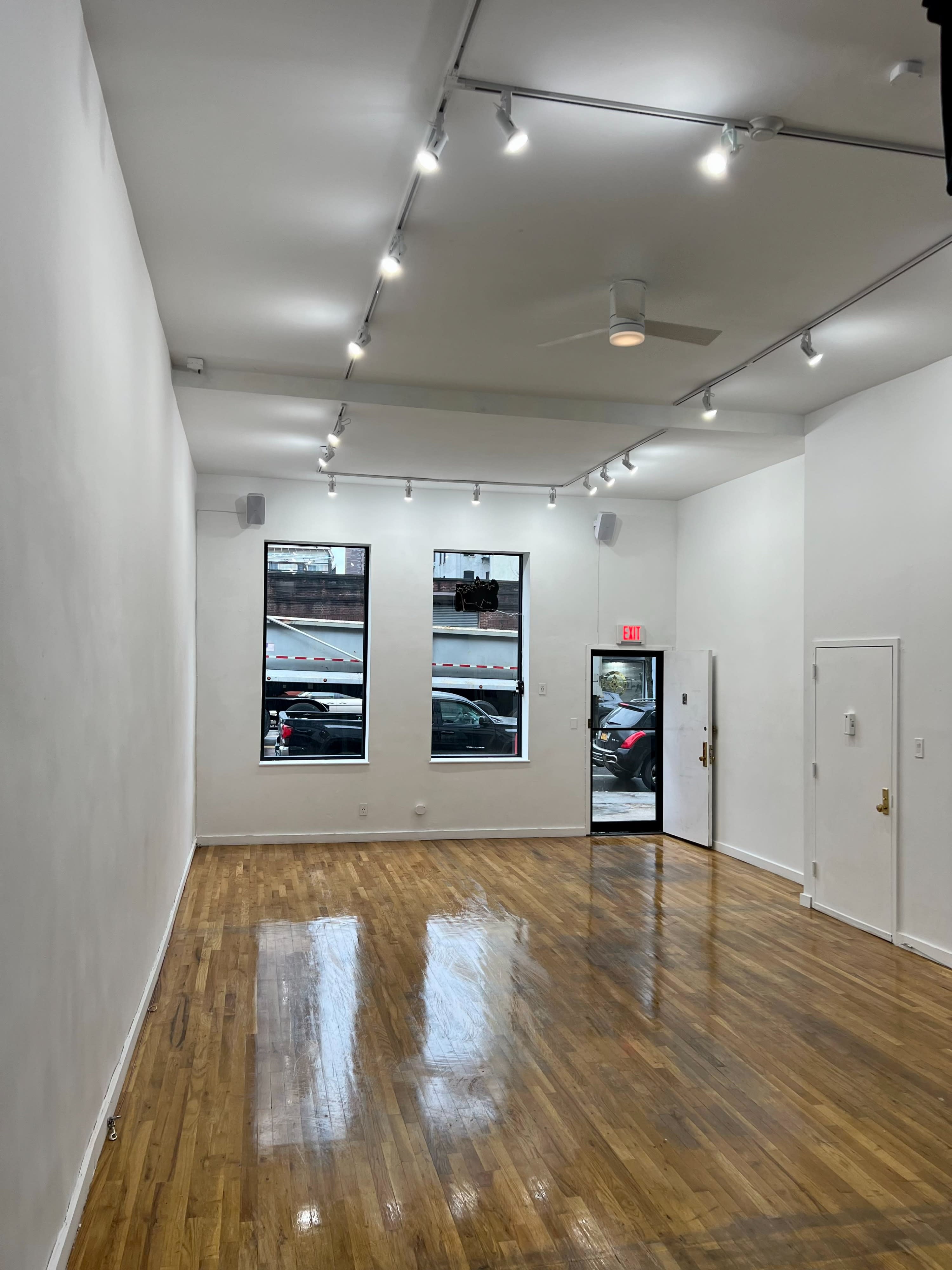 A DJ sets up equipment in an art gallery featuring photographs on the walls, with sunlight streaming through a large window.