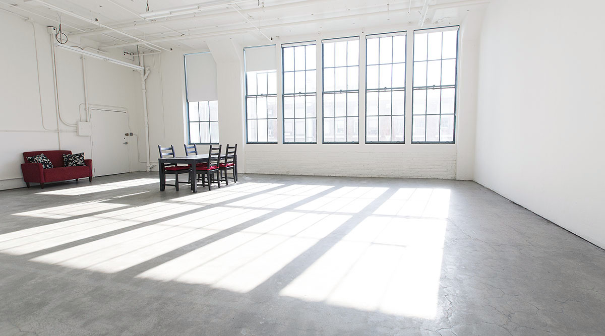 A couple sits close together on a soft mat, sharing a moment of intimacy in a bright, neutral space.