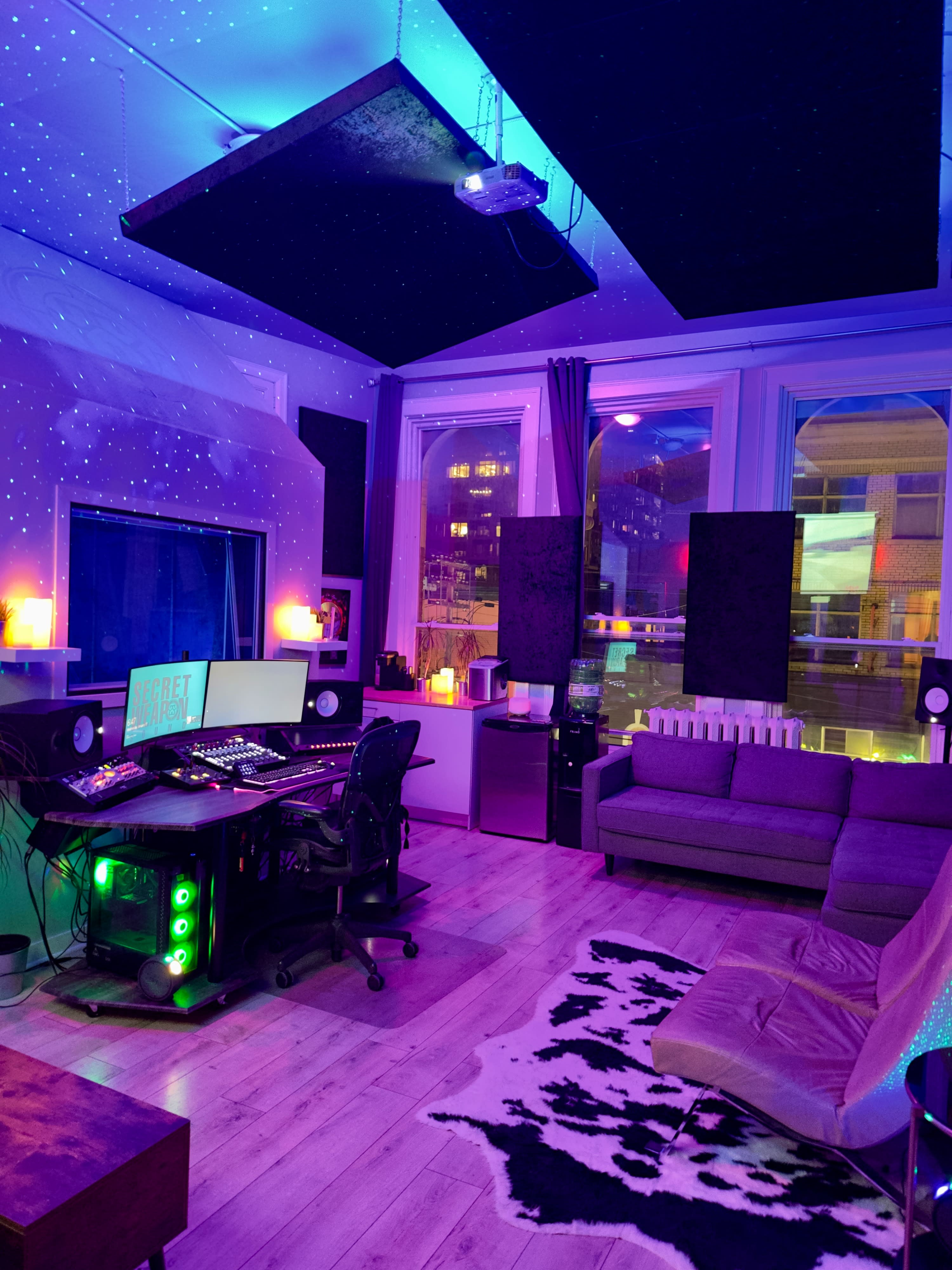 A person sits in a recording studio, positioned in front of a woman who is seated on a couch, as they engage in a music recording session.