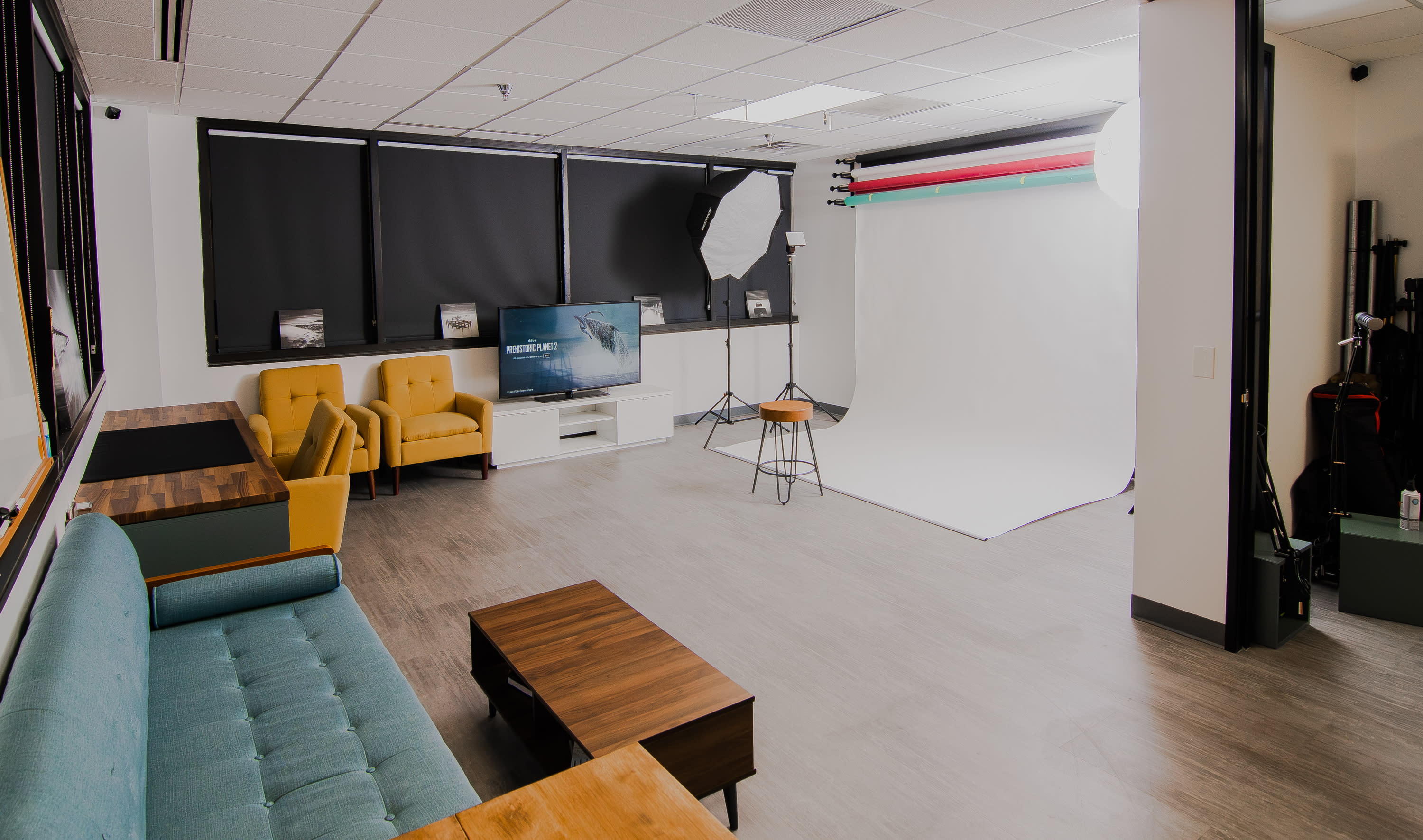 A person sits on a couch during a photoshoot in a studio with a world map backdrop.