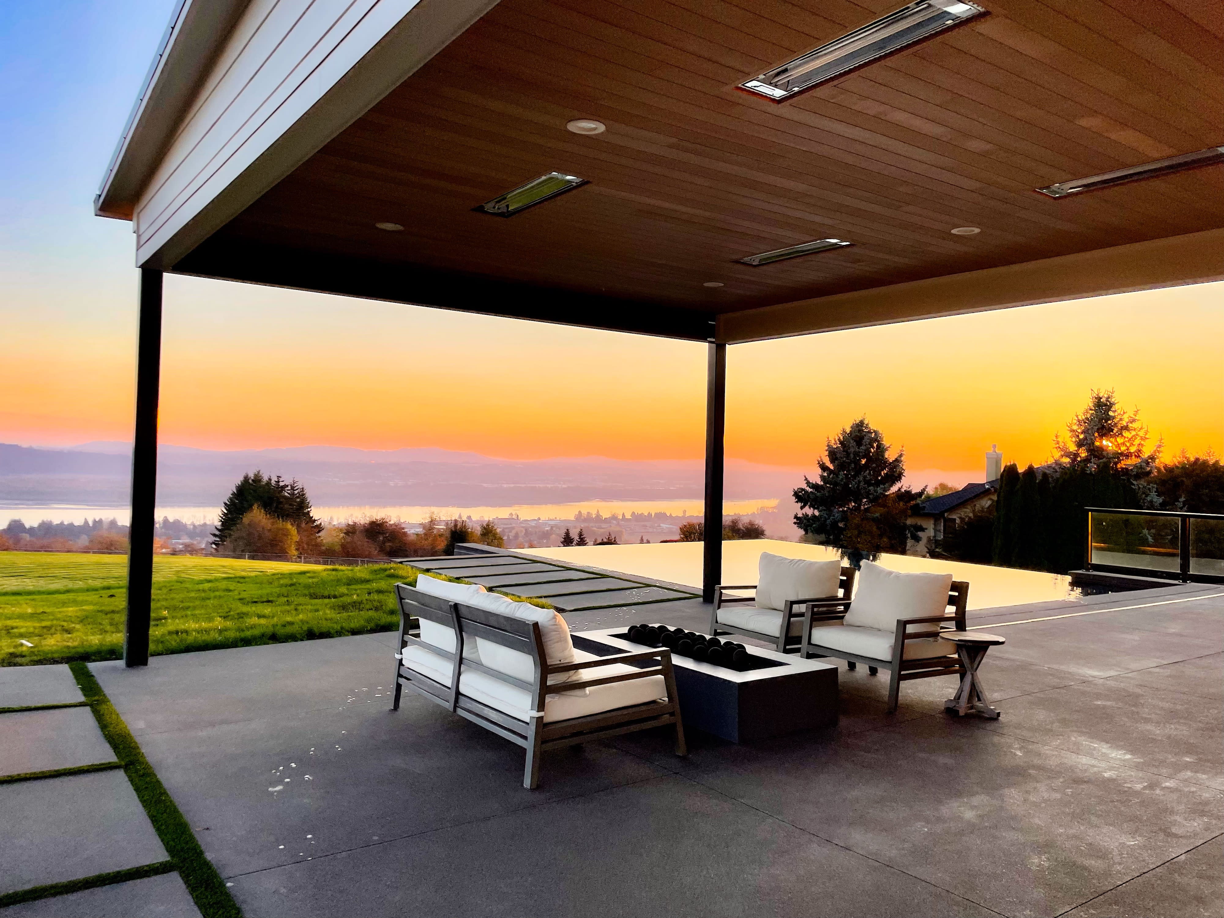 A fitness class is set up outdoors with rows of pink yoga mats arranged near a pool, overlooking a scenic landscape.